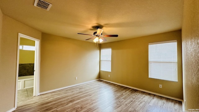 empty room with ceiling fan, light hardwood / wood-style flooring, and a textured ceiling