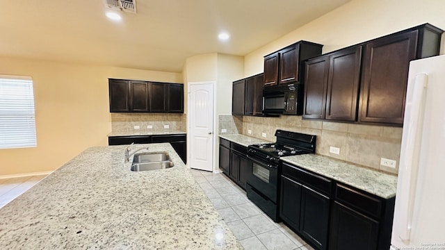 kitchen with light stone countertops, sink, tasteful backsplash, dark brown cabinets, and black appliances