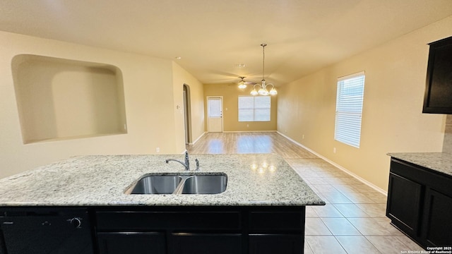 kitchen with light stone countertops, sink, pendant lighting, and ceiling fan with notable chandelier