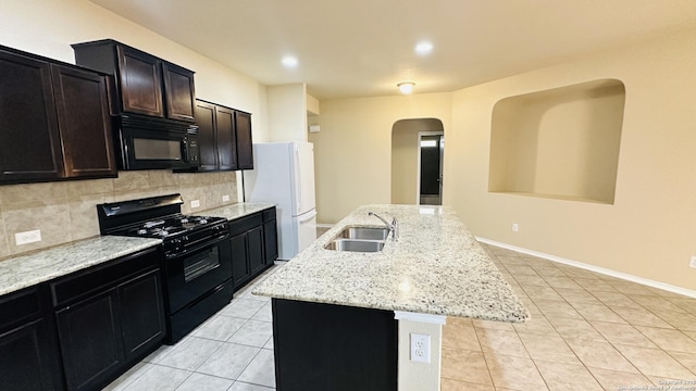 kitchen featuring tasteful backsplash, sink, black appliances, a center island with sink, and light tile patterned flooring