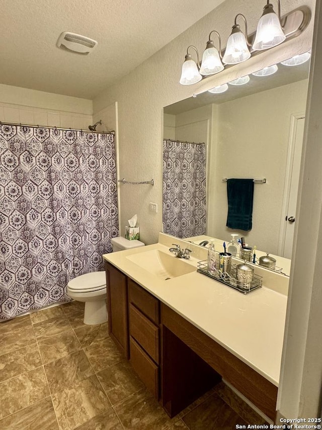 bathroom with vanity, a textured ceiling, and toilet