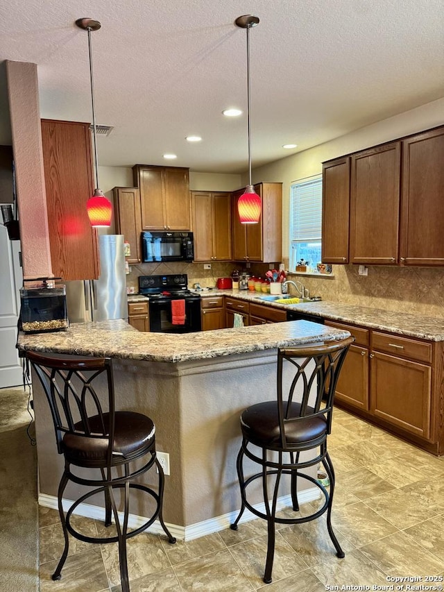 kitchen featuring pendant lighting, black appliances, a kitchen breakfast bar, sink, and light stone countertops