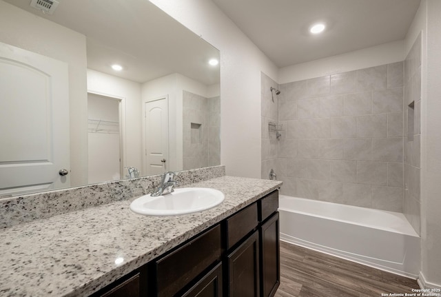 bathroom with vanity, hardwood / wood-style floors, and tiled shower / bath combo