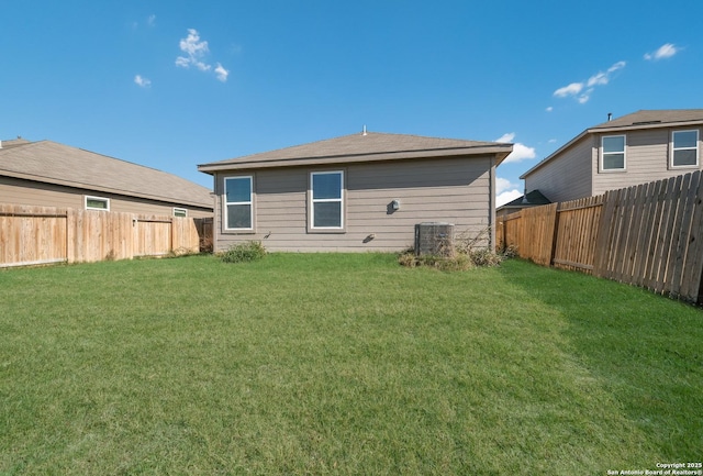 rear view of house with central AC and a lawn