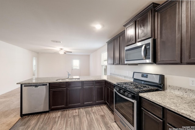 kitchen featuring kitchen peninsula, appliances with stainless steel finishes, light wood-type flooring, dark brown cabinetry, and sink