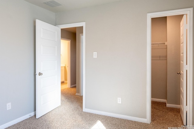 unfurnished bedroom featuring light carpet, a closet, and a spacious closet