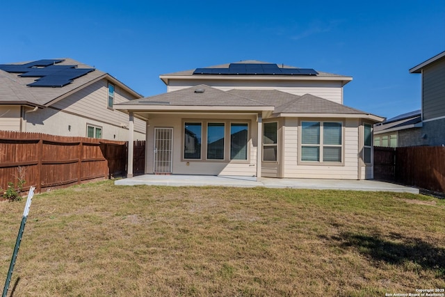 rear view of house featuring a lawn, a patio area, and solar panels