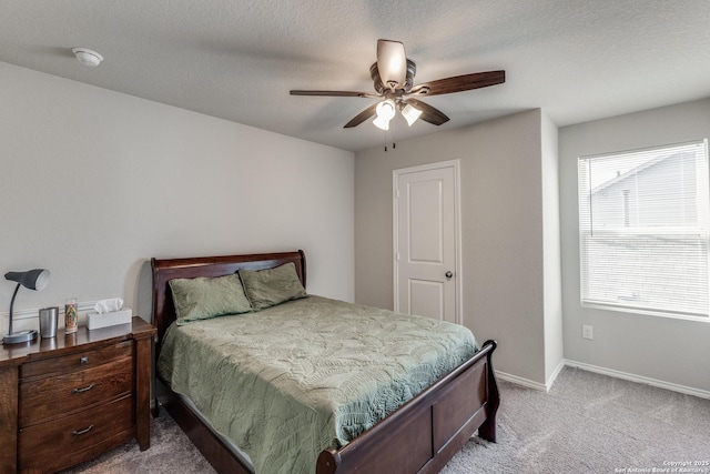 bedroom with a textured ceiling, light colored carpet, and ceiling fan