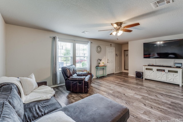 living room with hardwood / wood-style flooring, ceiling fan, and a textured ceiling