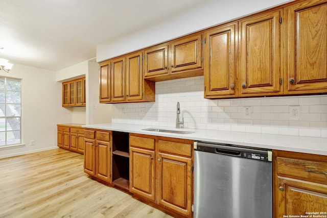 kitchen featuring dishwasher, sink, decorative backsplash, light wood-type flooring, and a chandelier