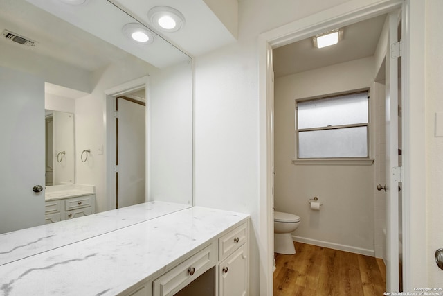 bathroom featuring wood-type flooring, vanity, and toilet