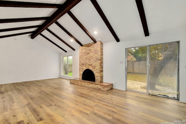 unfurnished living room with vaulted ceiling with beams, a fireplace, and light hardwood / wood-style floors