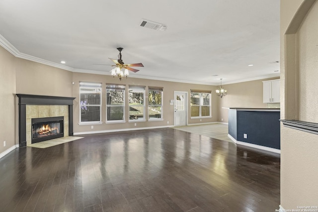 unfurnished living room with ceiling fan with notable chandelier, dark hardwood / wood-style flooring, ornamental molding, and a tile fireplace