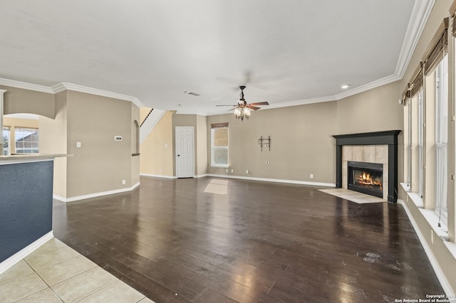 unfurnished living room with a tile fireplace, hardwood / wood-style floors, ceiling fan, and crown molding