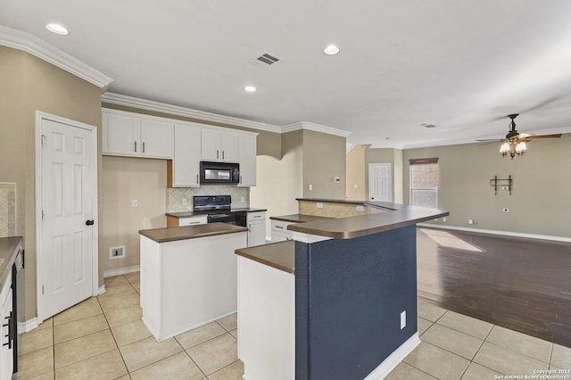 kitchen with ceiling fan, light tile patterned floors, a kitchen island, white cabinets, and black appliances