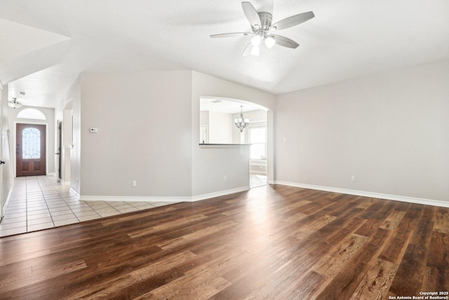 unfurnished living room with hardwood / wood-style floors, ceiling fan with notable chandelier, a textured ceiling, and a wealth of natural light