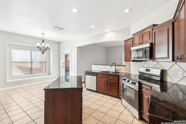 kitchen featuring sink, stainless steel appliances, an inviting chandelier, backsplash, and light tile patterned floors