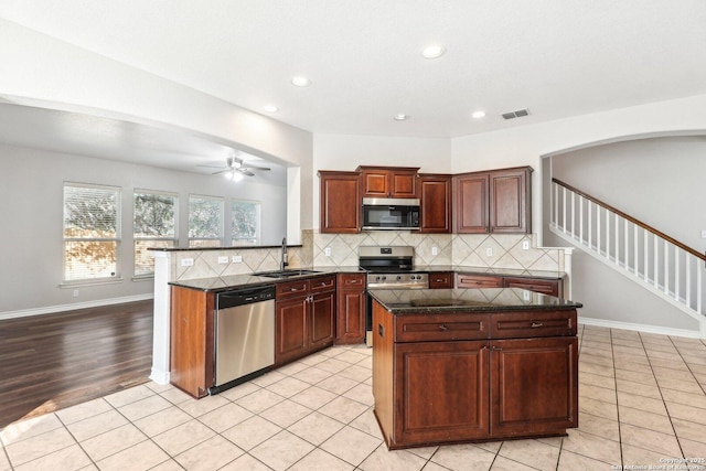 kitchen with sink, stainless steel appliances, backsplash, kitchen peninsula, and a kitchen island