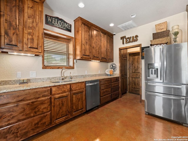 kitchen with light stone countertops, sink, appliances with stainless steel finishes, and concrete floors