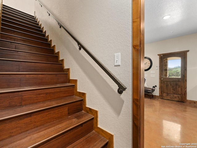 stairs featuring a textured ceiling