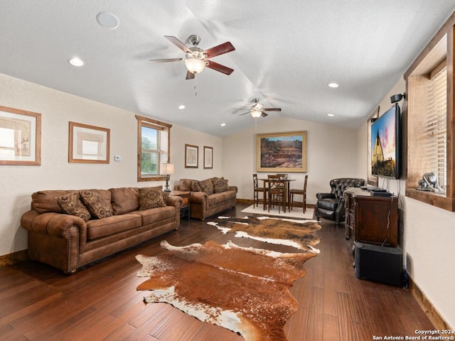 living room with a textured ceiling, vaulted ceiling, ceiling fan, and dark wood-type flooring