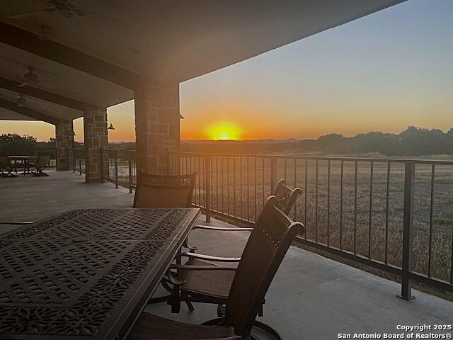 balcony at dusk featuring ceiling fan