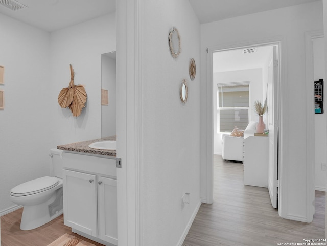 bathroom with hardwood / wood-style floors, vanity, and toilet