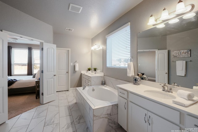 bathroom featuring tiled bath and vanity