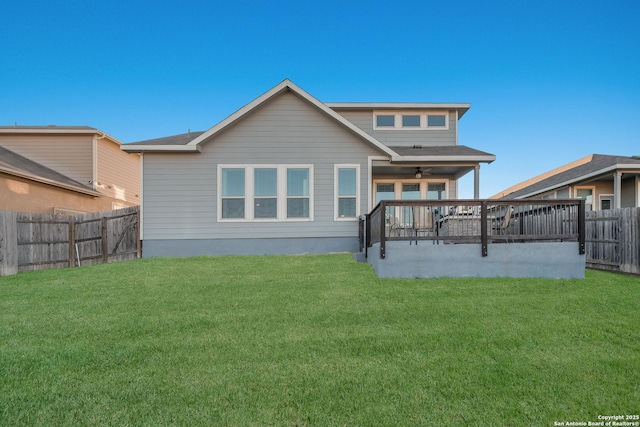 rear view of property featuring a lawn, ceiling fan, and a deck