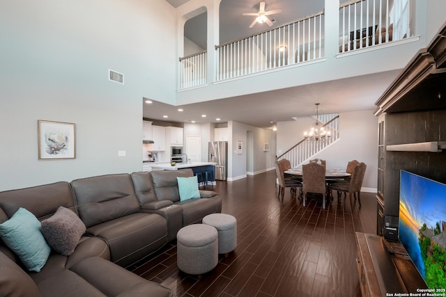 living room featuring ceiling fan with notable chandelier and a towering ceiling