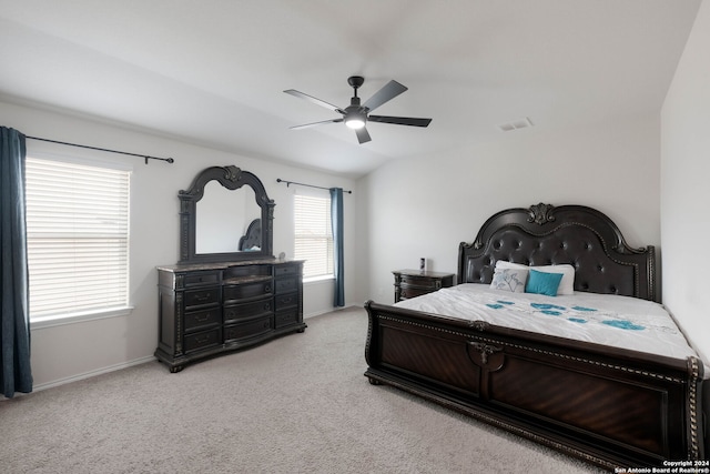 carpeted bedroom with multiple windows, ceiling fan, and vaulted ceiling