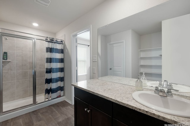 bathroom with hardwood / wood-style floors, vanity, and a tile shower