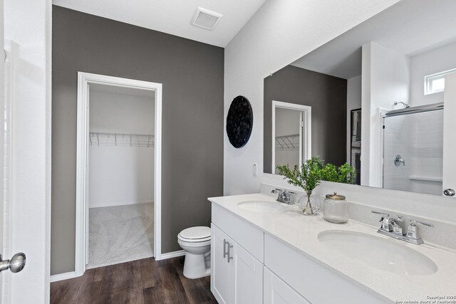 bathroom featuring a shower with door, vanity, hardwood / wood-style floors, and toilet