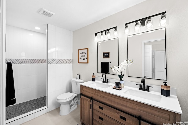 bathroom featuring tile patterned flooring, vanity, toilet, and tiled shower