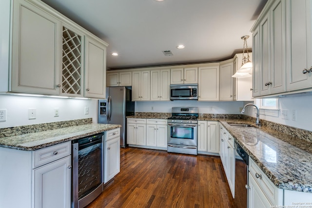 kitchen featuring appliances with stainless steel finishes, beverage cooler, sink, dark hardwood / wood-style floors, and hanging light fixtures