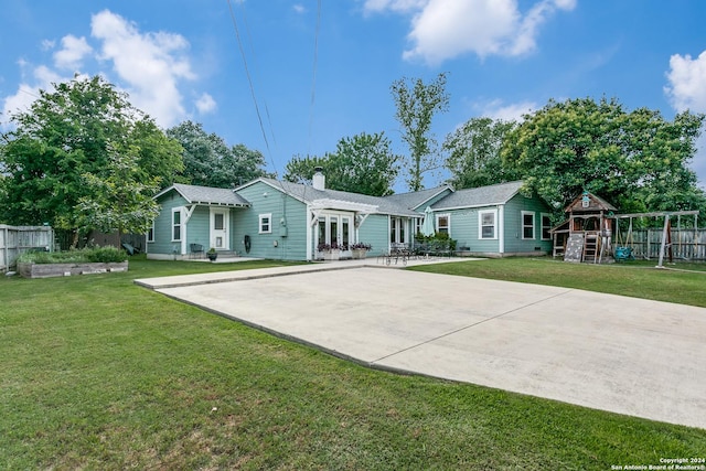 back of house featuring a playground and a yard