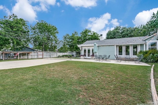 rear view of property with a lawn, a patio area, and french doors