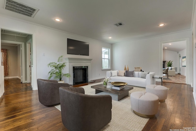 living room with a high end fireplace, dark hardwood / wood-style floors, and crown molding