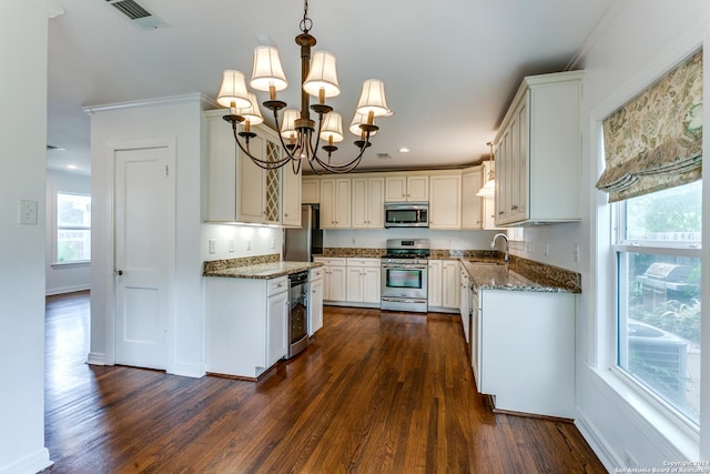 kitchen featuring an inviting chandelier, hanging light fixtures, dark hardwood / wood-style floors, dark stone countertops, and appliances with stainless steel finishes