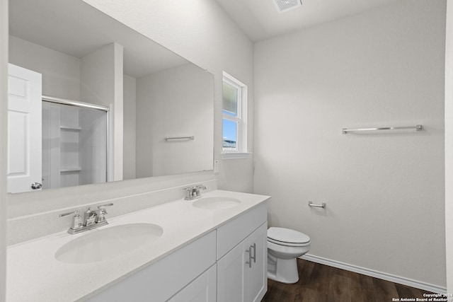 bathroom featuring wood-type flooring, vanity, toilet, and a shower with shower door