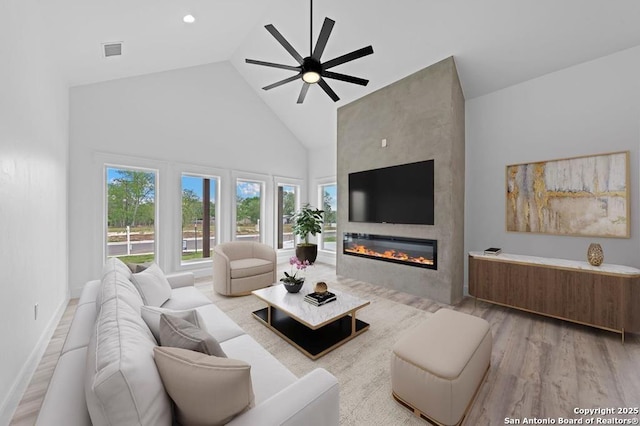 living room featuring wood-type flooring, a large fireplace, high vaulted ceiling, and ceiling fan