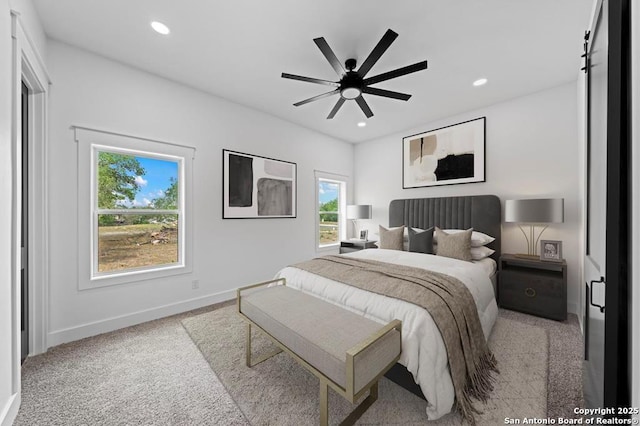 carpeted bedroom with a barn door and ceiling fan