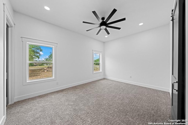 carpeted spare room featuring ceiling fan and a barn door