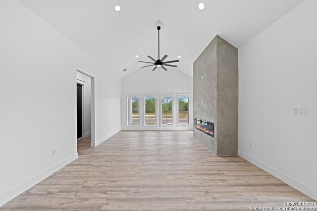 unfurnished living room with ceiling fan, a fireplace, high vaulted ceiling, and light hardwood / wood-style floors