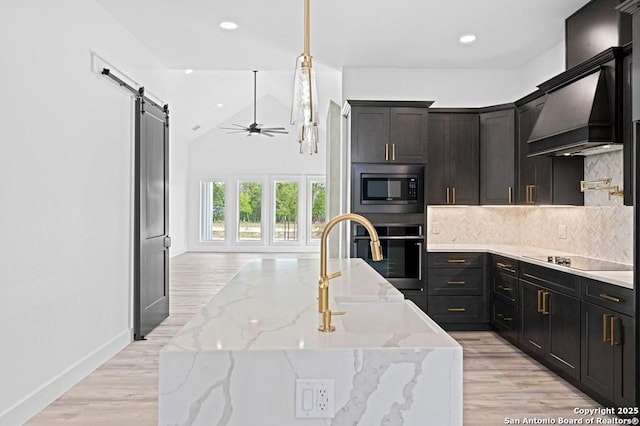 kitchen featuring black appliances, decorative backsplash, a barn door, ceiling fan, and light stone counters