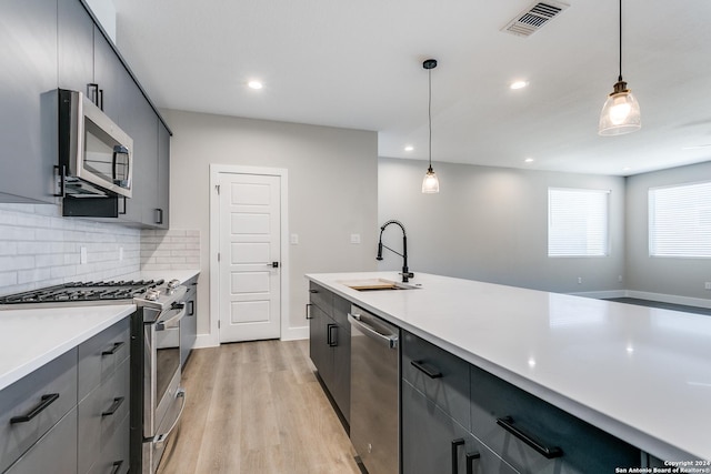 kitchen with pendant lighting, stainless steel appliances, tasteful backsplash, and sink