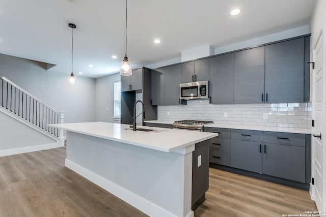 kitchen with gray cabinetry, sink, hanging light fixtures, backsplash, and appliances with stainless steel finishes