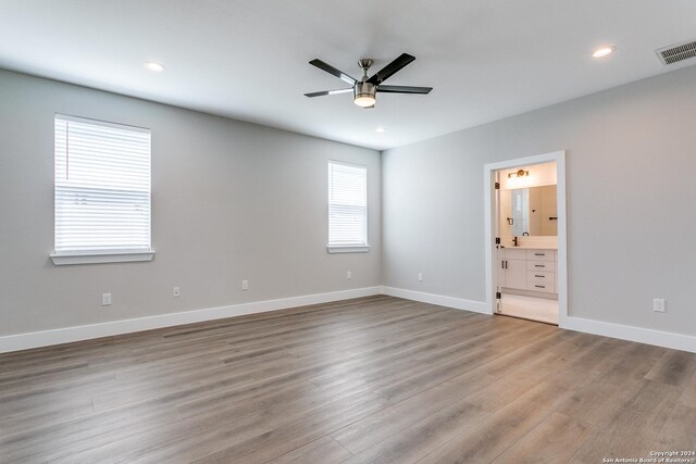 unfurnished bedroom with ensuite bathroom, ceiling fan, and light wood-type flooring