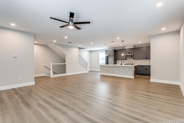 unfurnished living room featuring ceiling fan, light hardwood / wood-style floors, and sink