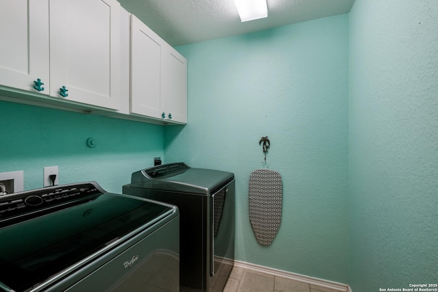 washroom featuring washing machine and clothes dryer, cabinets, and a textured ceiling